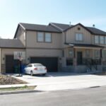 Plan 288-0265 Front view of a two-story home with a stone accent and garage